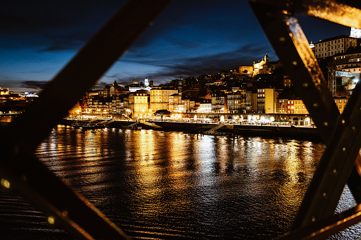 Night view of riverside in Porto with famous iron bridge in the front, Portugal
