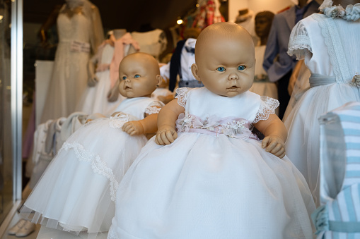 A bit spooky blue-eyed dolls in white dresses displayed in shop window, Porto, Portugal