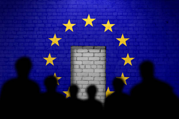 Silhouettes face a bricked-up doorway on a wall painted with the EU flag, symbolizing restricted access or immigration barriers.