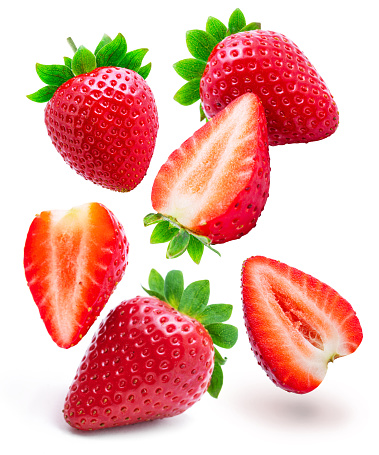 Flying in air strawberries and slices of strawberry isolated on white background.