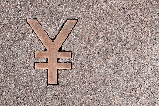 Copper weathered worn Yen sign in stone or asphalt on the road. Flat lay. Copy space