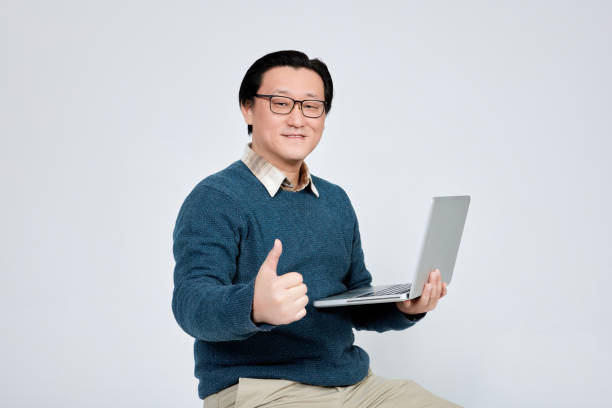 istock Happy businessman holding laptop in front of white background 1925006830