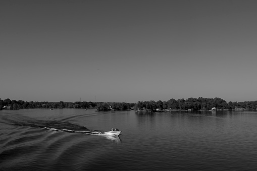 One of the thousand islands near Gananoque on Lake Ontario.  There is a leisure boat with people on it in the foreground.