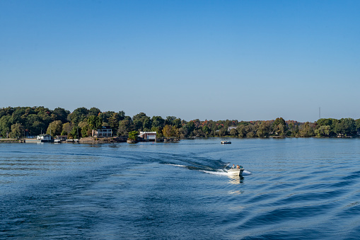 One of the thousand islands near Gananoque on Lake Ontario.  There is a leisure boat with people on it in the foreground.