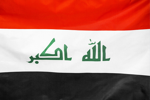 Fabric texture flag of Iraq. Flag of Iraq waving in the wind. Iraq flag is depicted on a sports cloth fabric with many folds. Sport team banner.