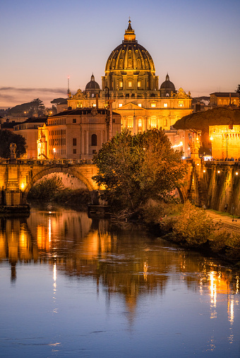Rome, Italy - The iconic dome of St Peter's Cathedral dominating the skyline in a view across the River Tiber at night.
