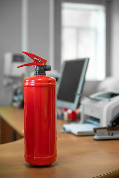 Fire extinguisher in workplace office against plain neutral background