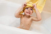 Portrait of adorable boy having fun while taking a bath with foam