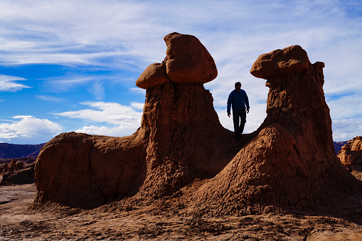 Man in Silhouette Standing Between Rock Hoodoo Formations - Goblin shaped rocks in surreal desert landscape.