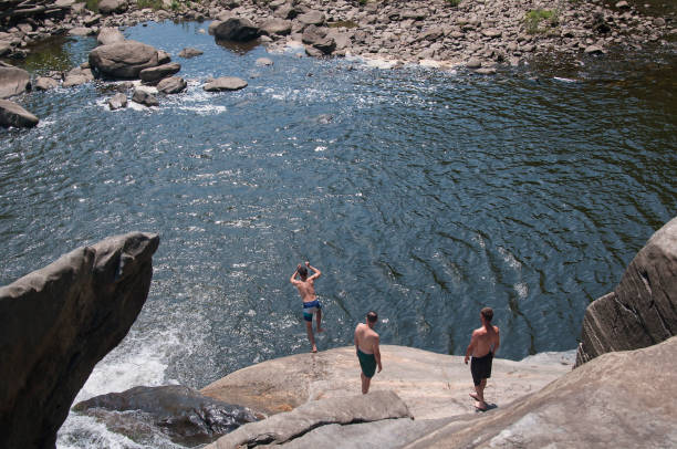 Canaan, Connecticut. July 28, 2019. A man jumping off of rocks into water at Great Falls in Falls Village Canaan Connecticut on a sunny summer day.