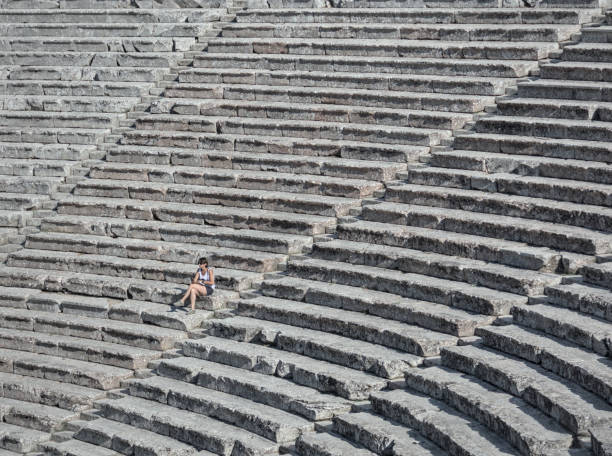 kobieta siedząca na krzesłach starożytnego greckiego teatru w epidavros, peloponez, grecja. - epidaurus greece epidavros amphitheater zdjęcia i obrazy z banku zdjęć