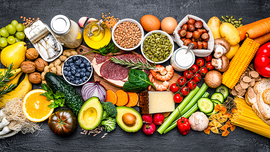 Overhead view of a large group of healthy food for a well balanced diet arranged side by side on black background. High resolution 42Mp studio digital capture taken with SONY A7rII and Zeiss Batis 40mm F2.0 CF lens