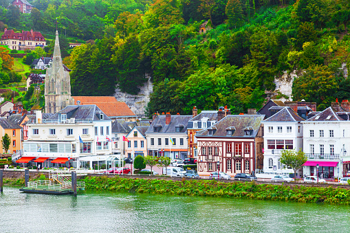 Rouen, France - 09.28.2023: The coast of the Seine River in France in the suburbs of Rouen with beautiful private houses and dense green vegetation and mountains.