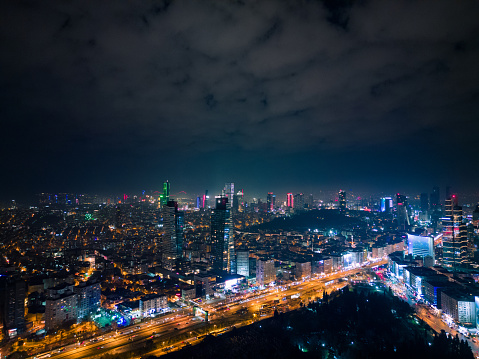 Istanbul's glass and concrete skyscrapers, home to offices, hotels, and residential complexes at night. Aerial drone view.