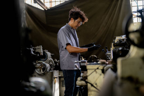 istock Asian worker in production plant drilling at machine. Professional worker near drilling machine on factory. finishing metal working internal steel surface on lathe grinder machine with flying sparks. 1925131422
