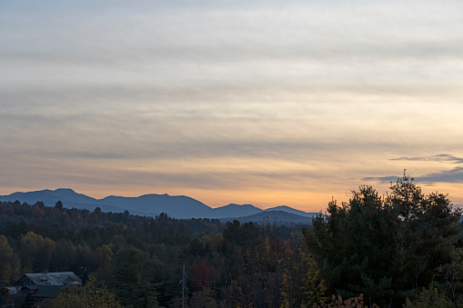 View at sunset over the autumnal leaf coloured forests near Mirror Lake, Lake Placid.  In the background are the Adirondack mountains.