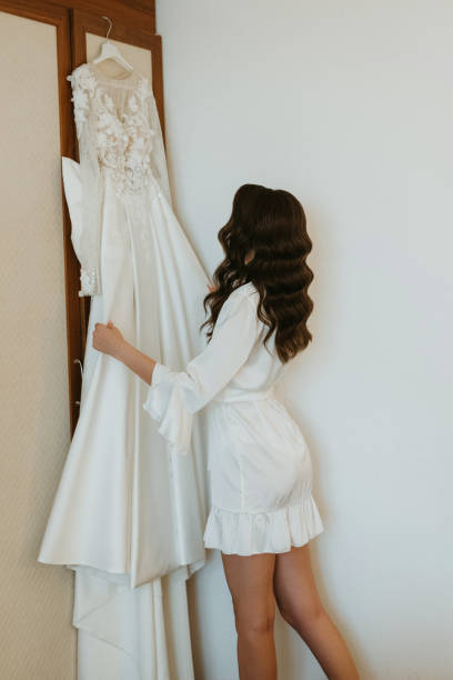 istock brown-haired girl puts on a wedding dress 1925150472