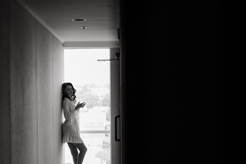 brown-haired girl in the morning in a bathrobe in the hotel corridor with a glass of white wine