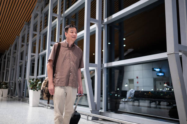 istock Asian business man pulling suitcase at airport terminal 1925152094