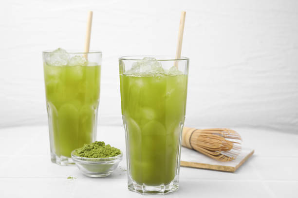 istock Delicious iced green matcha tea, powder and bamboo whisk on white table 1925164207