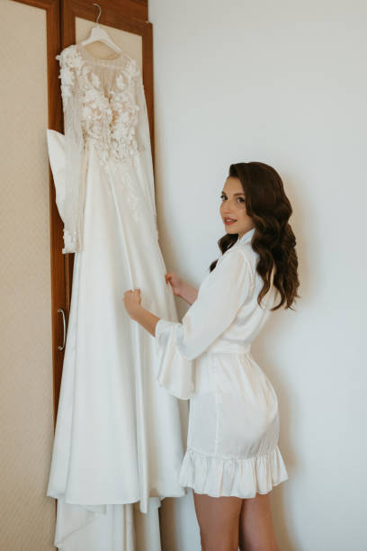istock brown-haired girl puts on a wedding dress 1925165269