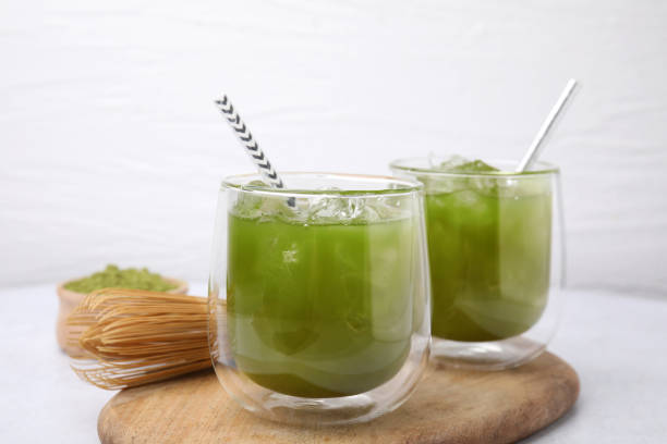 istock Delicious iced green matcha tea and bamboo whisk on white table, closeup 1925165809