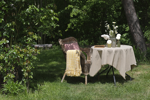 An outdoor metal table and two chairs with a background of summer grasses.