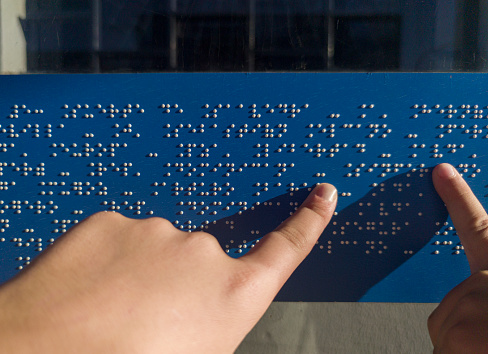 Child hands reading text caption in braille language at bus stop glass. Accesible transports concept