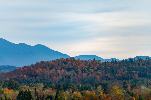 View at sunset over the autumnal leaf coloured forests near Mirror Lake, Lake Placid.  In the background are the Adirondack mountains.