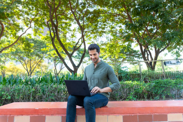 istock Happy Latin American man remotely working surrounded by trees for fresh air and relaxation using his laptop and internet for working together with his team. 1925190037