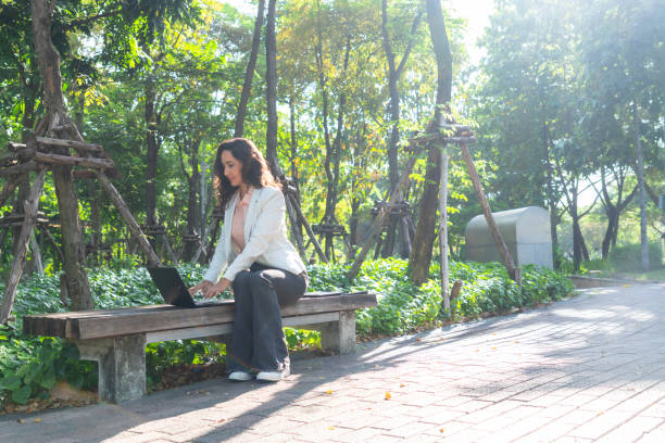 istock Latin American woman using wireless technology for supporting his hybrid work at the public park and meeting with his team for work flowing of the corporate business. 1925190583
