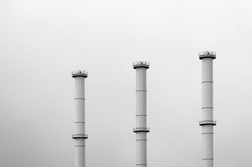 three industrial chimneys against a gray sky