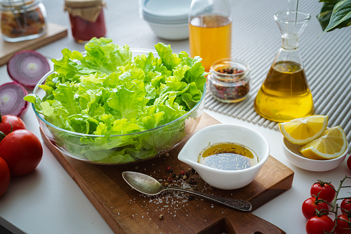 Healthy lettuce salad on kitchen counter. Ingredients like tomatoes, onion salad oil, pepper, salt and lemon complete the composition. High resolution 42Mp studio digital capture taken with SONY A7rII and Zeiss Batis 40mm F2.0 CF lens