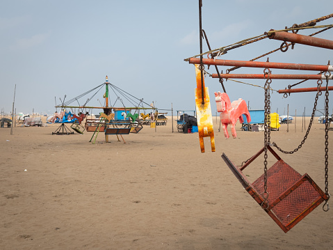 Carousel with wooden horses in beach for kids fun. Merry go round as part of fun activities in Marina Beach, Chennai, India.