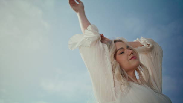 istock Portrait model summer sky illuminated sunlight. Woman waving hands to camera. 1925238687