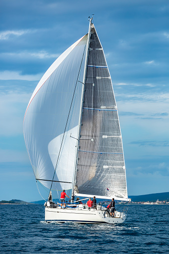 A light blue sailboat is sailing peacefully in Frenchman Bay around the porcupine islands in Bar Harbor Maine.