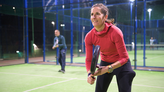 Padel tennis player ready to serve during a friendly match at night