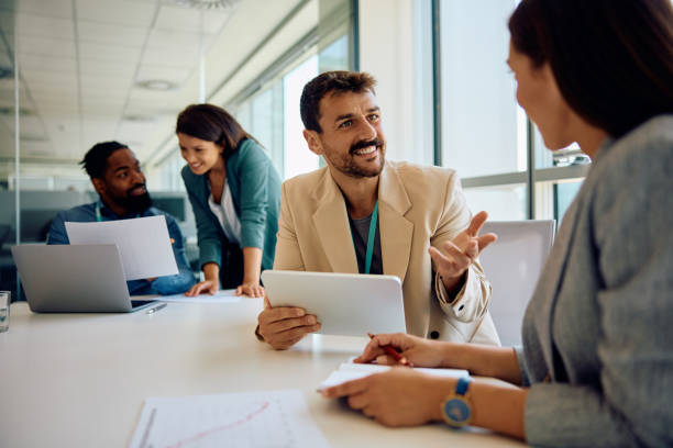 istock Happy businessman using touchpad while talking to coworker during the meeting. 1925292172