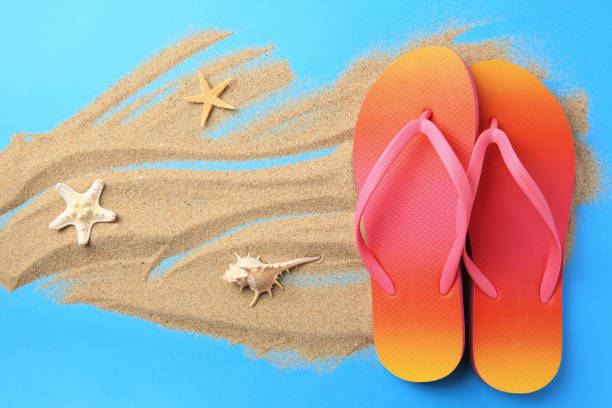 istock Flip flops and sand on light blue background, flat lay. Beach accessories 1925325633