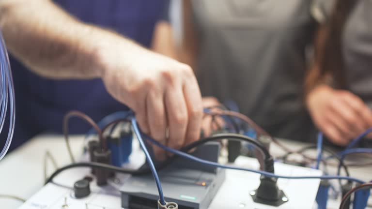 Close Up Of Teacher Connecting And Operating PLC Device During High School Class