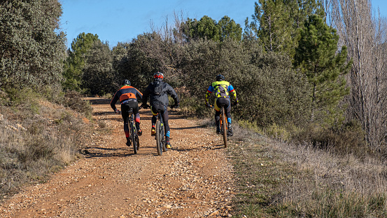 Lozoya del Valle, Madrid, Spain., 06/12/2021: Three cyclists on bicycles through the countryside in the mountains of Madrid during the day going up a rural road in the middle of nature