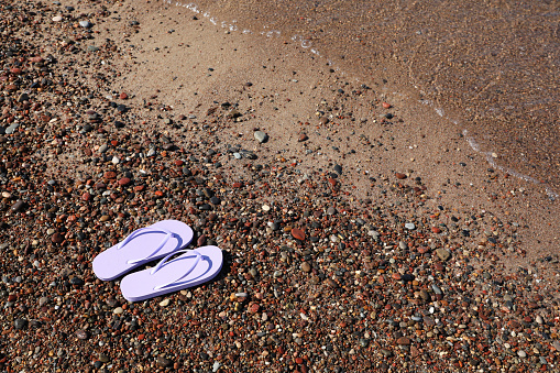 Stylish violet flip flops on beach pebbles, above view. Space for text