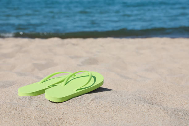 istock Stylish light green flip flops on beach sand, space for text 1925348899