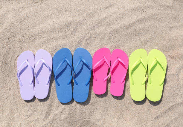 istock Many stylish colorful flip flops on sand outdoors, flat lay 1925350016