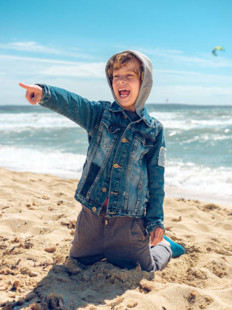 istock Happy boy pointing finger at distance on beach 1925359372