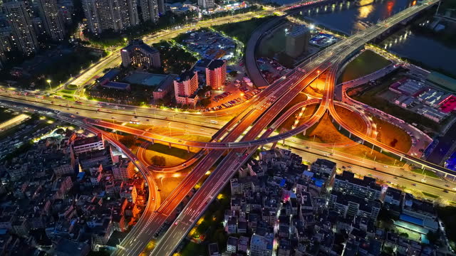 Aerial pan shot of city road intersection with car traffic at night
