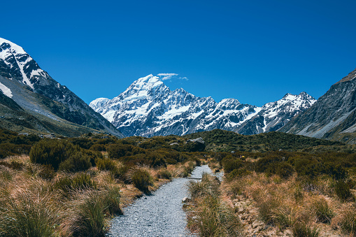 Discover the picturesque landscape in New Zealand's South Island leading to the renowned Mount Cook mountain. Behold the stunning sight of snow-capped Mount Cook, majestically framed by other towering mountain peaks. In front the Hooker Valley trail.