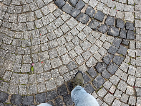 Point of view of feet on a cobblestone street. Walking away.