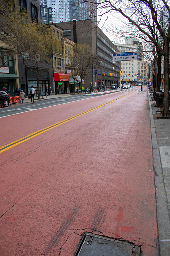 Nyc, United States – January 07, 2024: A city street has two lanes of red asphalt in parallel, with a manhole cover in the center