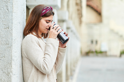 Woman outdoors drinking from a reusable cup